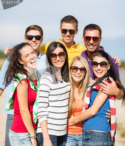 Image of group of happy friends hugging on beach