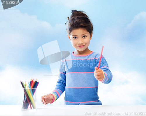 Image of happy little girl drawing with coloring pencils