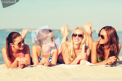 Image of group of smiling women in sunglasses on beach