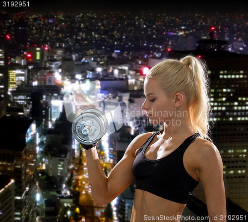 Image of young sporty woman with heavy steel dumbbell