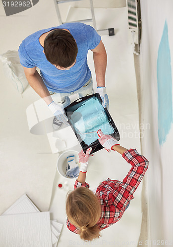 Image of couple with paint roller painting wall at home