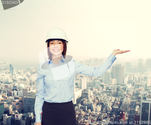 Image of businesswoman in helmet holding something on palm