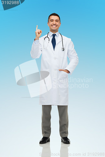 Image of happy male doctor in white coat pointing finger up