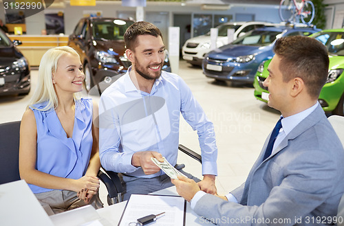 Image of happy couple with car dealer in auto show or salon