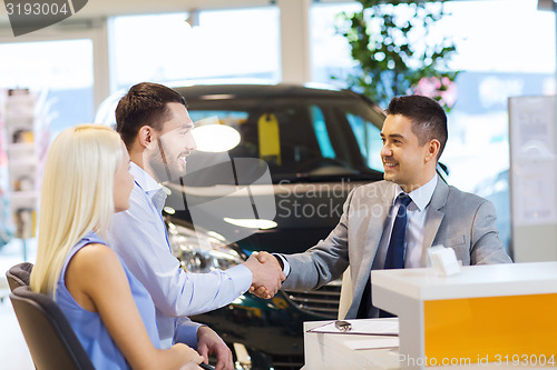 Image of happy couple with car dealer in auto show or salon