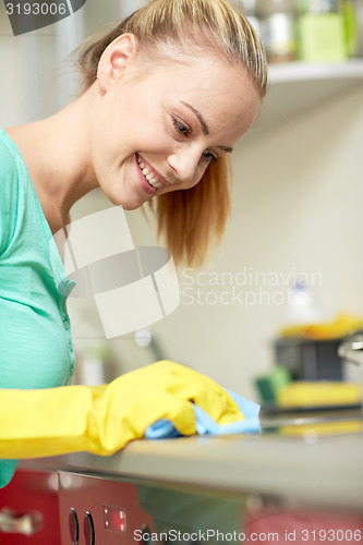 Image of happy woman cleaning cooker at home kitchen