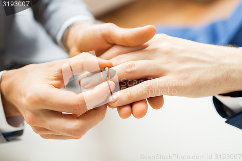 Image of close up of male gay couple hands and wedding ring