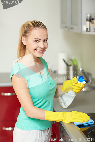 Image of happy woman cleaning cooker at home kitchen