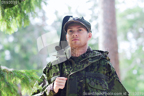 Image of young soldier or hunter with gun in forest