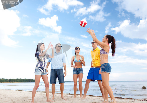 Image of group of happy friends playing beach ball