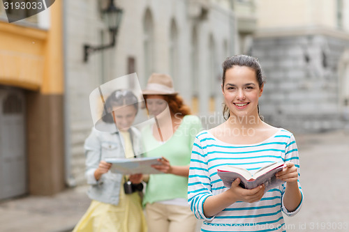 Image of smiling teenage girls with city guides and camera