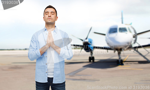 Image of man praying over airplane on runway background