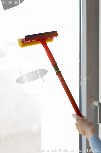 Image of close up of hand cleaning window with sponge