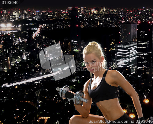 Image of young sporty woman with heavy steel dumbbell