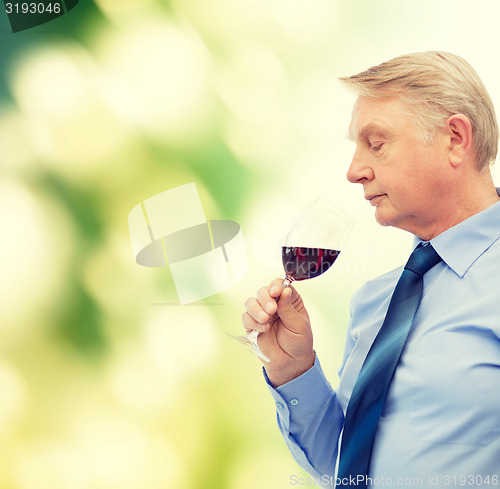 Image of elderly man smelling red wine