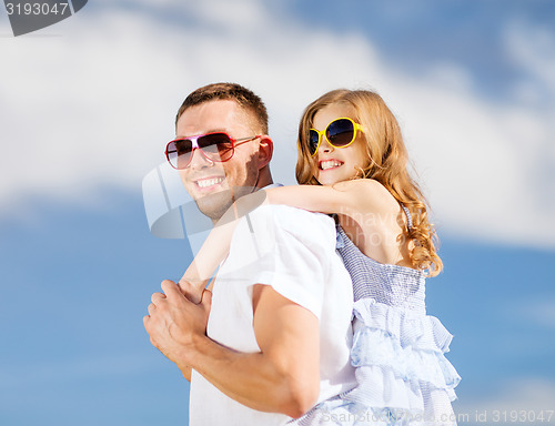 Image of happy father and child in sunglasses over blue sky