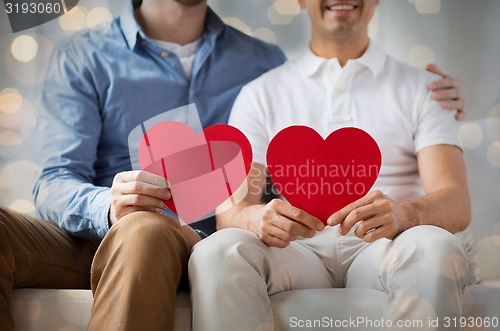 Image of close up of happy gay male couple with red hearts