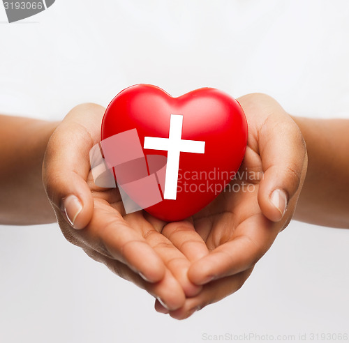 Image of female hands holding heart with cross symbol