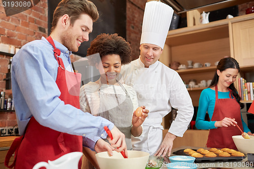 Image of happy friends and chef cook baking in kitchen