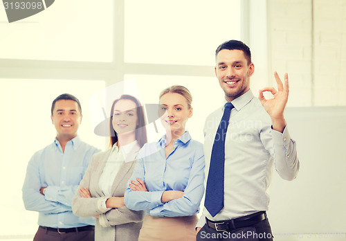 Image of smiling businessman showing ok-sign in office