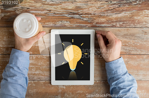 Image of close up of hands with ligting bulb on tablet pc