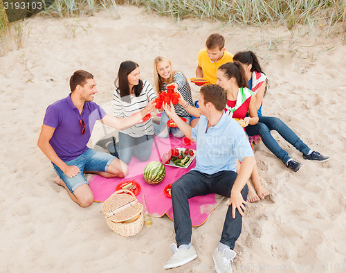 Image of group of happy friends having picnic on beach