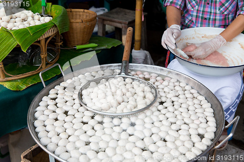 Image of meat or rice balls frying in oil at street market