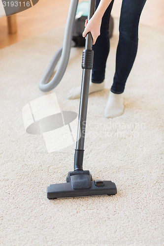 Image of close up of woman legs with vacuum cleaner at home