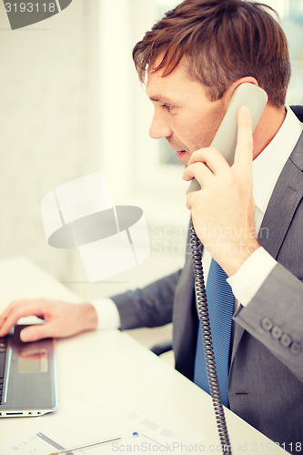 Image of businessman with laptop computer and phone