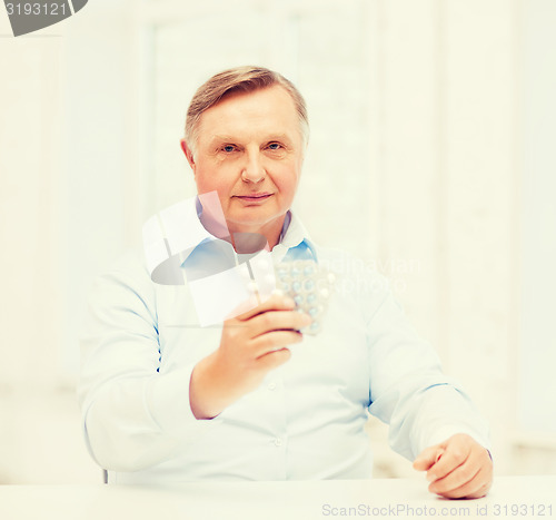 Image of old man with pack of pills