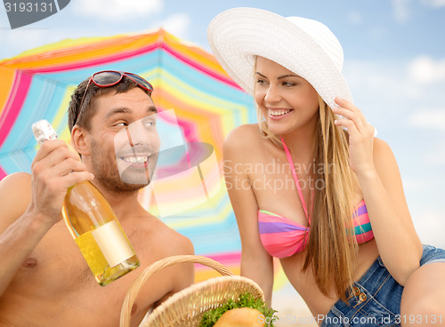 Image of chappy ouple having picnic and sunbathing on beach