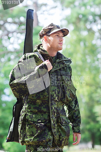 Image of young soldier or hunter with gun in forest