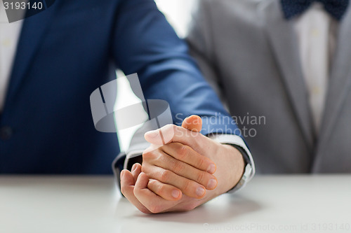 Image of close up of happy male gay couple holding hands