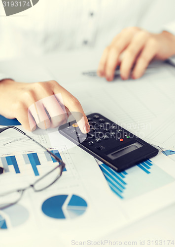 Image of woman hand with calculator and papers