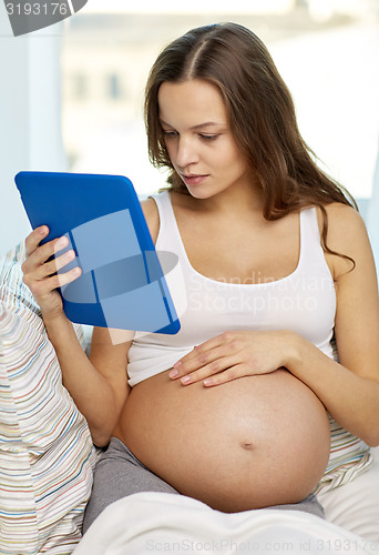 Image of happy pregnant woman with tablet pc at home