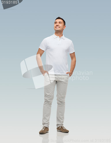 Image of smiling man with hands in pockets looking up