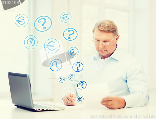 Image of old man in eyeglasses filling a form at home