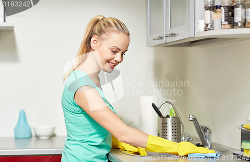 Image of happy woman cleaning table at home kitchen