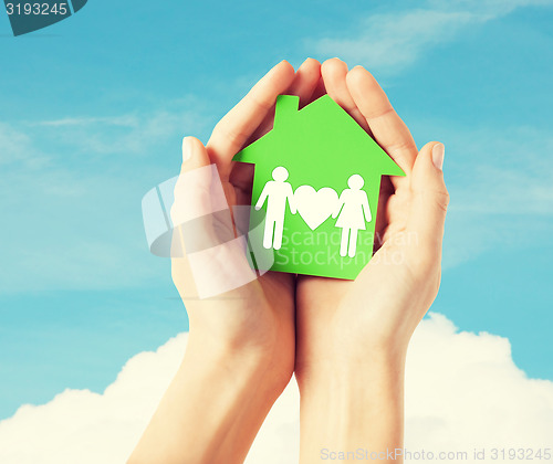 Image of hands holding green house with family