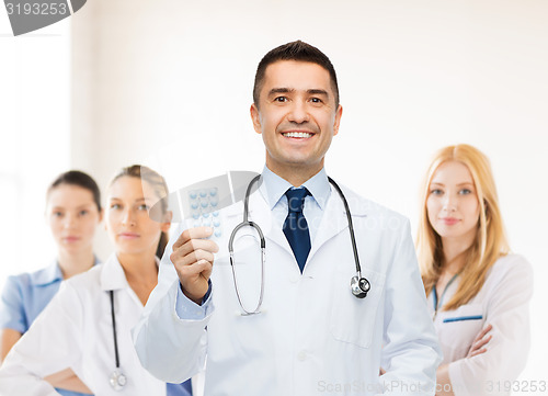 Image of smiling male doctor in white coat with tablets