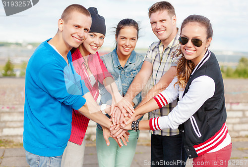 Image of teenagers hands on top of each other outdoors