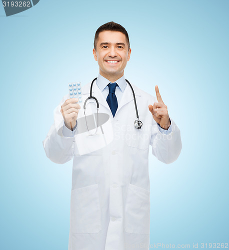Image of smiling male doctor in white coat with tablets