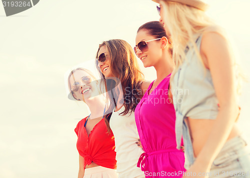 Image of group of smiling women in sunglasses on beach