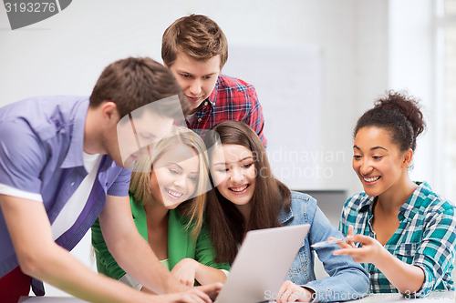 Image of international students looking at laptop at school