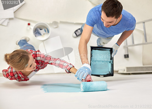 Image of couple with paint roller painting wall at home