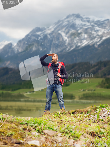 Image of tourist with beard and backpack looking far away