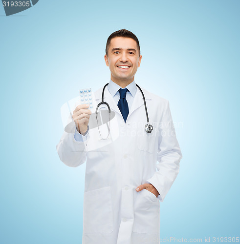 Image of smiling male doctor in white coat with tablets