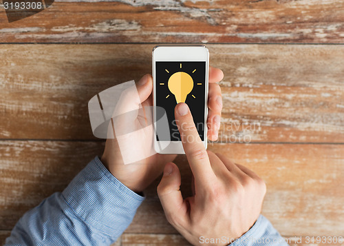 Image of close up of male hands with smartphone on table