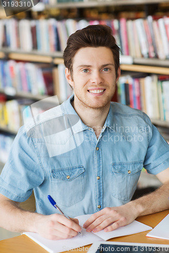 Image of happy student writing to notebook in library