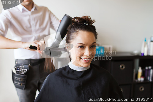 Image of happy woman with stylist making hairdo at salon